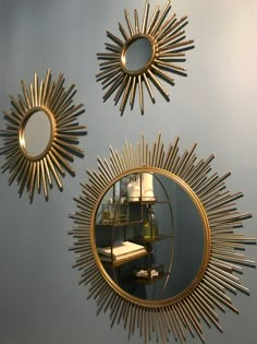 three sun shaped mirrors hanging on the wall