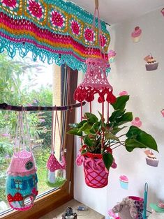 a potted plant in a hanging basket next to a window with cupcakes on it