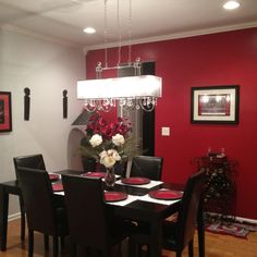 a dining room table with black chairs and red walls