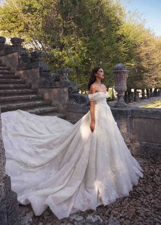 a woman in a white wedding dress standing on some rocks and looking off to the side