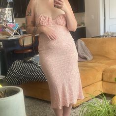 a woman taking a selfie in her living room while wearing a pink polka dot dress