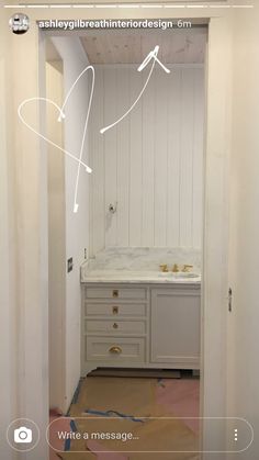 an open door leading to a bathroom with white cabinets and drawers on the wall,