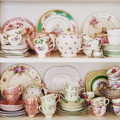 the shelves are filled with china and plates, cups and saucers in different colors