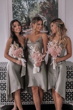 three bridesmaids in grey dresses holding bouquets