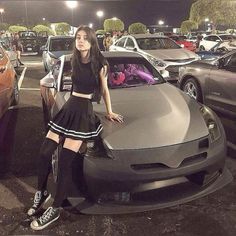 a woman standing next to a car in a parking lot