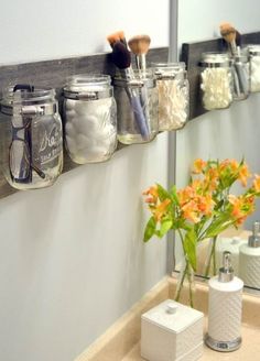 mason jars are lined up on the wall to hold makeup brushes and other personal care items