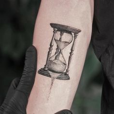 a person with a tattoo on their arm has an hourglass in the middle of it