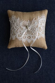 a white lace pillow with a ring on it's side, tied to a burlock