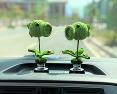 two crocheted flowers are placed on the dashboard of a car