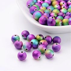 purple and green speckled beads next to a white bowl filled with pinkish speckled beads