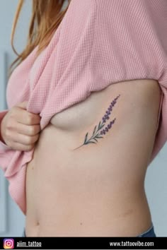 a woman's stomach with a small lavender tattoo on her side, which is also part of the belly