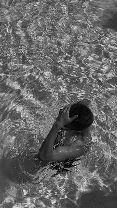 a man swimming in the ocean with his hat on