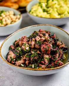 a bowl filled with meat and vegetables on top of a table next to other bowls