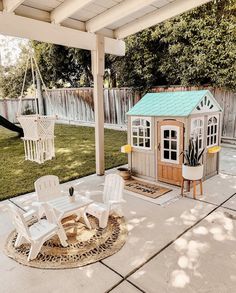 a small wooden house sitting on top of a patio next to a white lawn chair