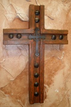 a wooden cross with metal rivets on the sides against a stone wall in a church