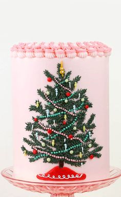 a decorated christmas tree on top of a pink cake