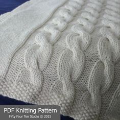 a white knitted blanket sitting on top of a blue bed cover with the words knitting pattern