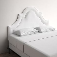 a white bed with two pillows on top of it