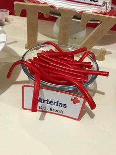 a bowl filled with red rubber bands sitting on top of a table next to a sign that says arteerias