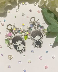 two keychains are sitting next to some flowers