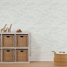 a toy giraffe on top of a dresser next to baskets and a wallpaper