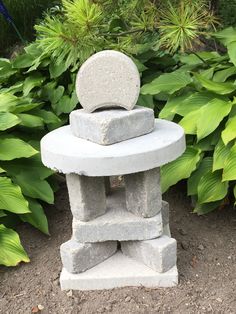 a stone sculpture sitting in the middle of a garden