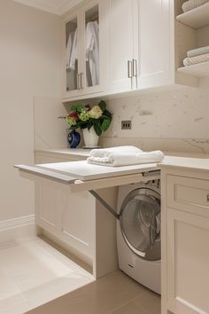 a washer and dryer in a room with white cupboards on the wall