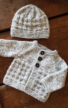 a knitted sweater, hat and booties sitting on top of a wooden table