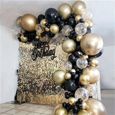 black, gold and white balloons are arranged on the floor