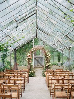 the inside of a greenhouse with rows of wooden chairs set up for an outdoor ceremony