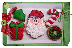 decorated cookies in the shape of santa claus and other holiday treats on a white tray