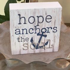 a wooden block with the words hope anchors the soul on it and an anchor sitting in front of a potted plant