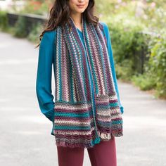 a woman wearing a multicolored crocheted scarf and matching leggings