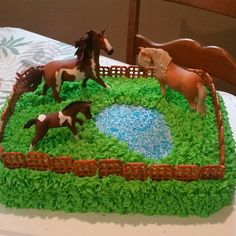 a cake that has horses on it and grass in the shape of a farm scene