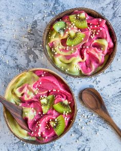 two bowls filled with kiwi fruit and topped with sprinkles next to a wooden spoon