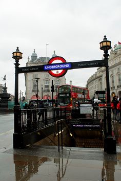 a red double decker bus driving down a street next to a sign that says underground