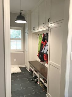 a walk in closet filled with lots of coats and shoes on top of shelves next to a window