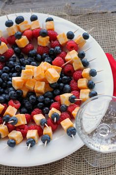 a white plate topped with fruit and cheese on skewers