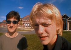 two young men standing next to each other in front of a building