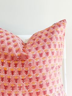 a pink and orange pillow sitting on top of a white bed