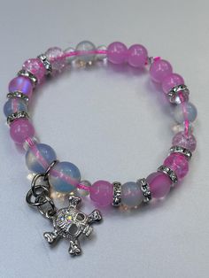 This stunning Opalite bracelet features a vibrant mix of pink beads, complemented by a unique charmed skull for a touch of edgy elegance. Opalite, known for its serene and calming energy, enhances personal power and emotional balance. It is believed to improve communication, clear mental blockages, and help with transitions, making it a perfect companion for navigating life's changes. The soft, iridescent glow of Opalite symbolizes purity and spiritual growth, while the pink beads add a gentle, Adjustable Pink Charm Bracelet With 8mm Beads, Trendy Pink Beaded Charm Bracelet, Pink Charm Bracelet With Round Beads For Friendship, Pink Round Beads Charm Bracelet For Friendship, Pink Charm Bracelet With 8mm Beads, Pink Spiritual Charm Bracelet For Friendship, Pink 8mm Beads Stretch Bracelet For Friendship, Pink Stretch Bracelet With 8mm Beads For Friendship, Pink Friendship Bracelet With 8mm Beads