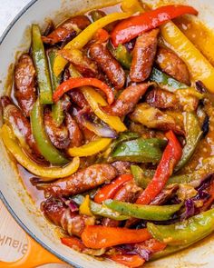 a pan filled with sausage and peppers on top of a table