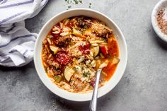 a bowl filled with pasta and vegetables next to two bowls of seasoning on the side