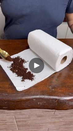 a person with a knife cutting into a roll of toilet paper on top of a wooden table