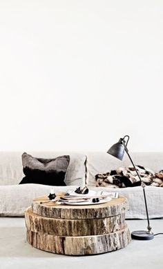 a living room filled with furniture and a tree stump table in front of the couch