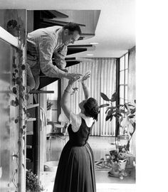 a woman standing on top of a ladder while another woman reaches up to reach her head