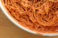 a bowl filled with spaghetti on top of a wooden table