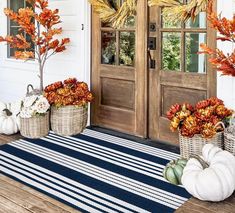 the front porch is decorated for fall with pumpkins and gourds in baskets