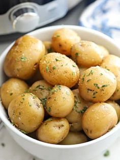 a white bowl filled with potatoes on top of a table next to an instant pressure cooker