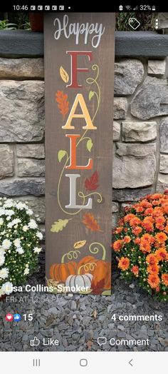 a wooden sign that says happy fall with leaves on it and flowers in the background